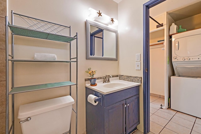 bathroom featuring toilet, tile patterned floors, stacked washing maching and dryer, and vanity