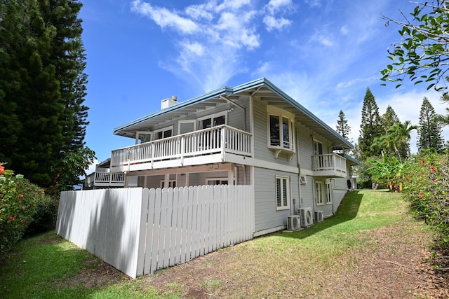 rear view of house with a balcony and a yard