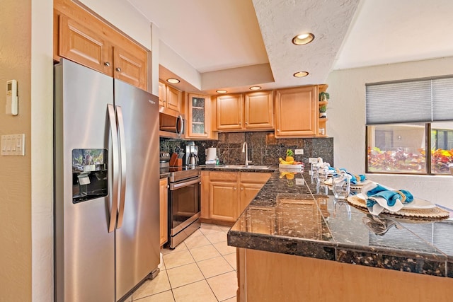 kitchen featuring sink, light tile patterned floors, kitchen peninsula, stainless steel appliances, and decorative backsplash