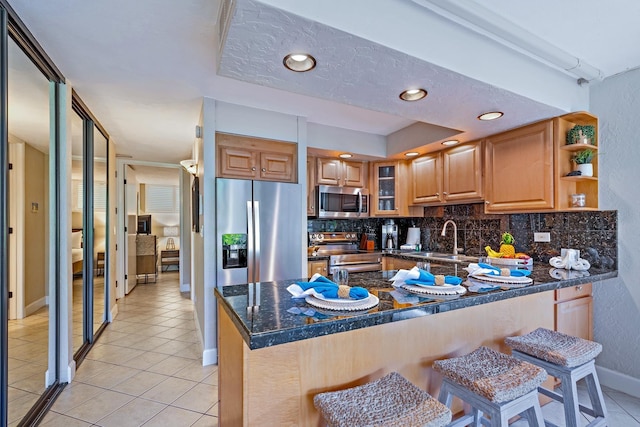 kitchen with tasteful backsplash, stainless steel appliances, kitchen peninsula, and sink