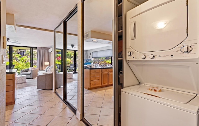 laundry room with light tile patterned floors, ceiling fan, and stacked washer / dryer