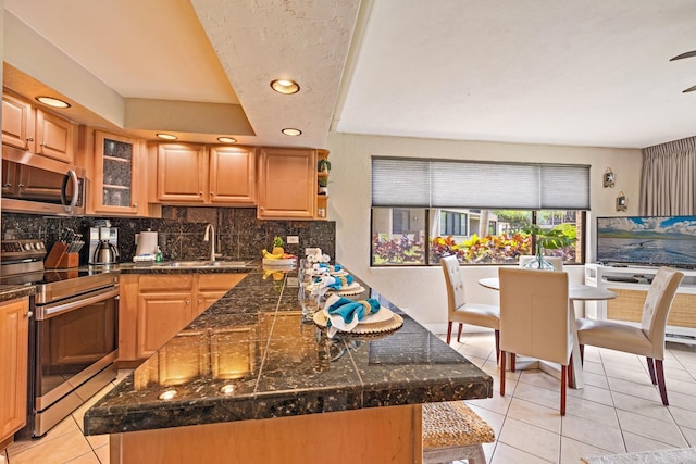 kitchen with sink, stainless steel appliances, a tray ceiling, light tile patterned flooring, and decorative backsplash