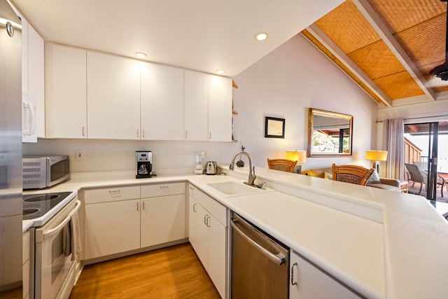 kitchen featuring vaulted ceiling, sink, white cabinetry, light hardwood / wood-style floors, and stainless steel appliances