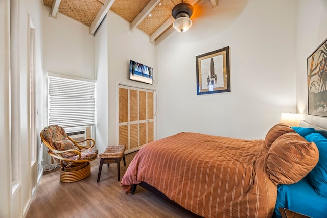 bedroom featuring ceiling fan, hardwood / wood-style floors, high vaulted ceiling, and beamed ceiling