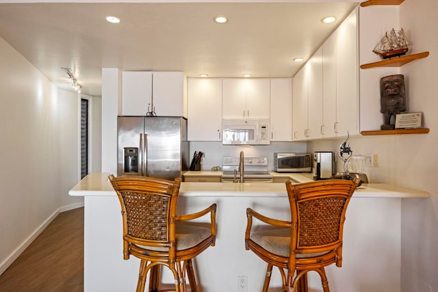 kitchen with stainless steel appliances, white cabinetry, kitchen peninsula, and dark hardwood / wood-style flooring