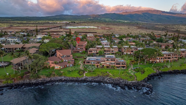 aerial view at dusk featuring a water and mountain view