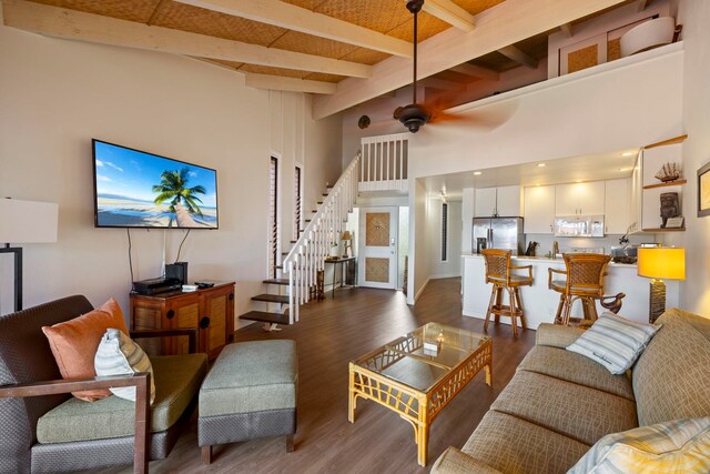 living room featuring dark wood-type flooring, beam ceiling, a high ceiling, and ceiling fan