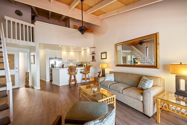 living room featuring dark hardwood / wood-style flooring, beam ceiling, and a towering ceiling