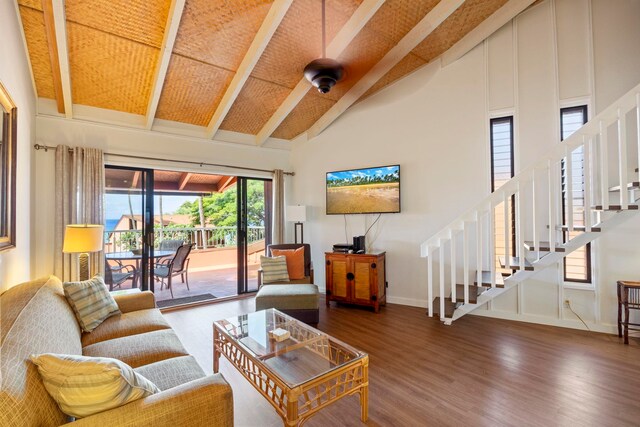 living room with beamed ceiling, dark wood-type flooring, a towering ceiling, and wooden ceiling