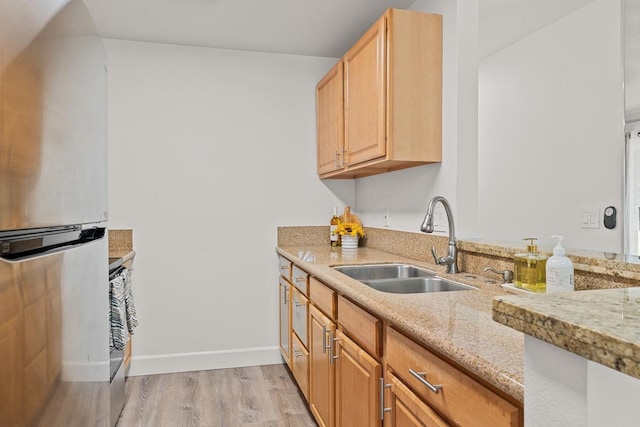 kitchen featuring light stone counters, light wood-type flooring, light brown cabinetry, refrigerator, and sink