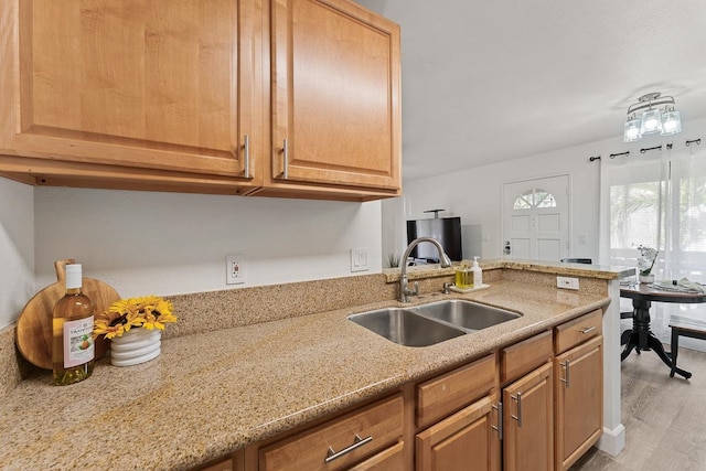 kitchen with light stone countertops, light hardwood / wood-style floors, and sink