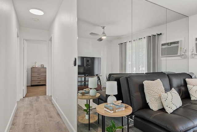 living room with light wood-type flooring, a wall unit AC, and ceiling fan