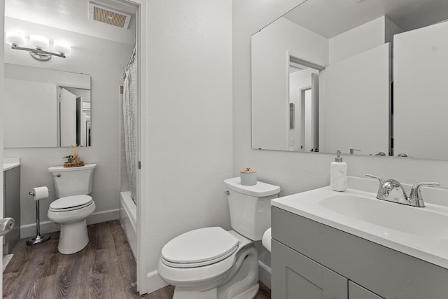 full bathroom featuring shower / bath combo with shower curtain, hardwood / wood-style flooring, vanity, and toilet