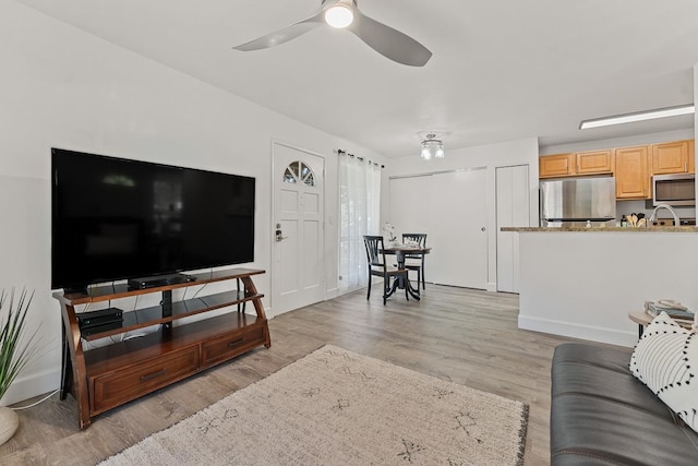 living room featuring light wood-type flooring, sink, and ceiling fan