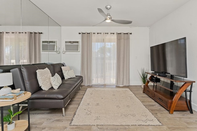 living room with light hardwood / wood-style flooring, an AC wall unit, and ceiling fan