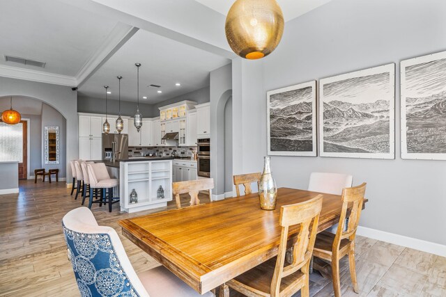 dining space featuring ornamental molding and light hardwood / wood-style flooring