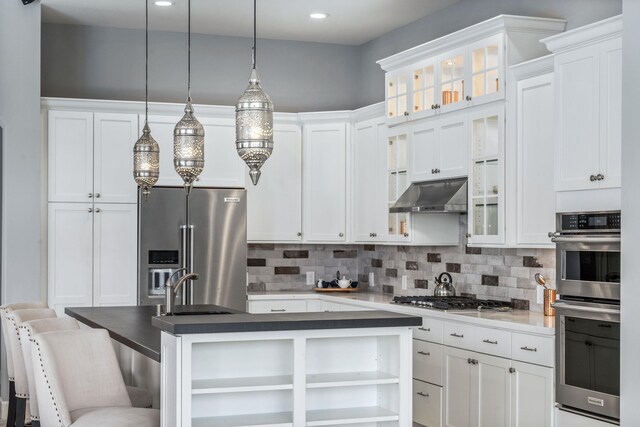 kitchen featuring backsplash, appliances with stainless steel finishes, white cabinets, and wall chimney exhaust hood