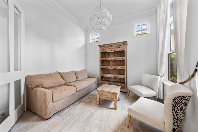 living room with an inviting chandelier, wood-type flooring, and ornamental molding