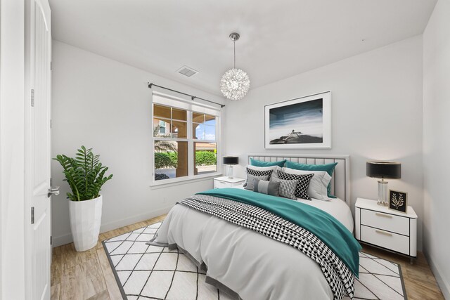 bedroom with a chandelier and light wood-type flooring