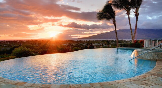 pool at dusk featuring a mountain view