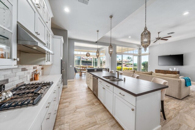 kitchen with white cabinets, a center island with sink, a breakfast bar, backsplash, and light tile patterned floors