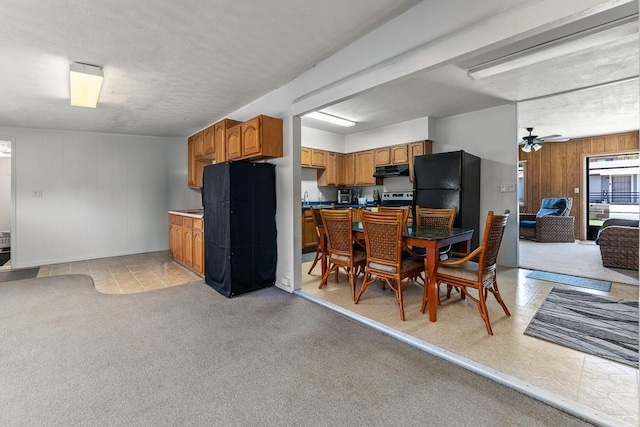 119 Kupalaiki Loop, Kihei, HI 96753 - kitchen with under cabinet range hood, open floor plan, brown cabinetry, wooden walls, and freestanding refrigerator