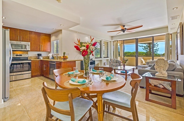 dining area with ceiling fan, sink, and light tile patterned flooring