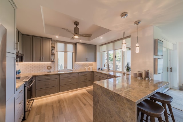 3200 Wailea Alanui Dr Unit 1606, Kihei, HI 96753 - kitchen with stainless steel electric range, a peninsula, gray cabinets, light stone counters, and decorative backsplash