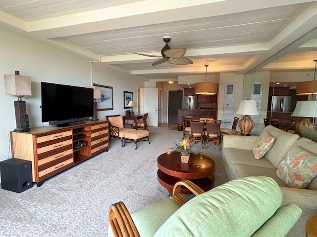 living room featuring ceiling fan, beamed ceiling, and carpet