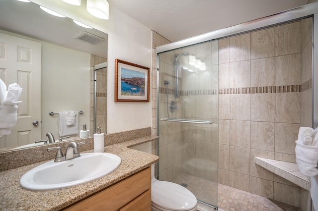 bathroom featuring a shower with door, vanity, and toilet