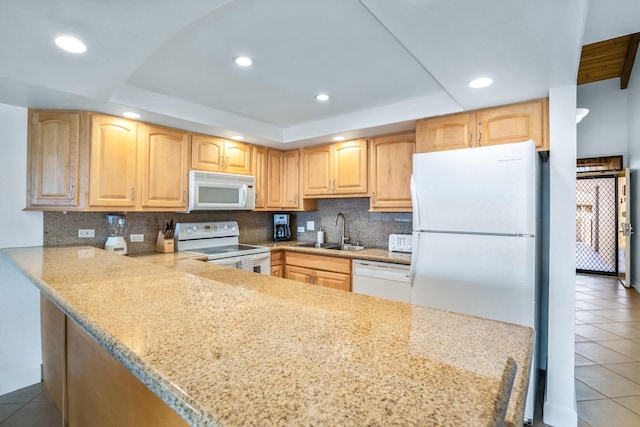 kitchen featuring dark tile patterned flooring, a raised ceiling, white appliances, and sink