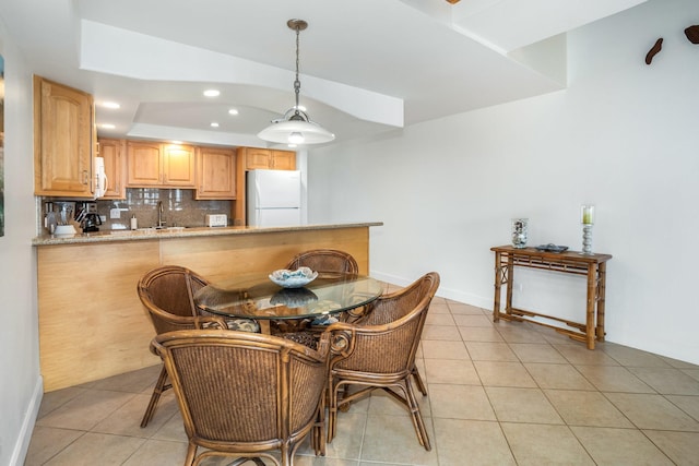 dining area with light tile patterned floors, a raised ceiling, and sink