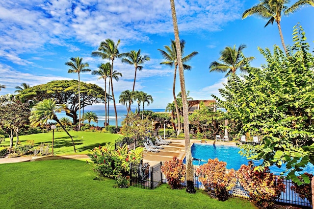 view of swimming pool featuring a water view and a lawn