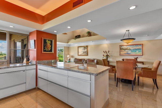 kitchen featuring a healthy amount of sunlight, kitchen peninsula, light tile floors, and white cabinetry