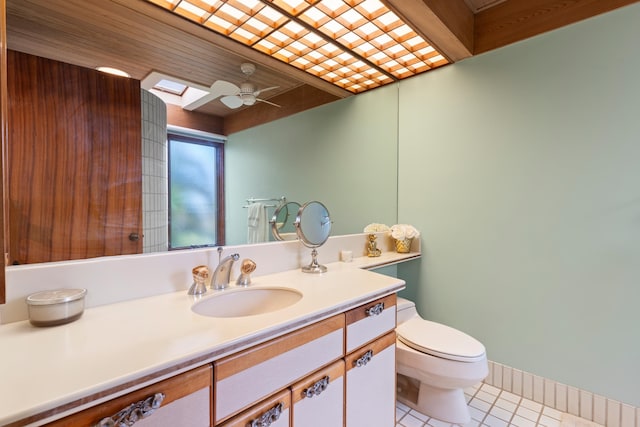 bathroom with a skylight, ceiling fan, tile floors, toilet, and vanity