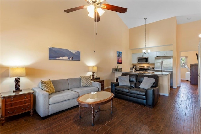 living room featuring ceiling fan with notable chandelier, dark wood-type flooring, and high vaulted ceiling