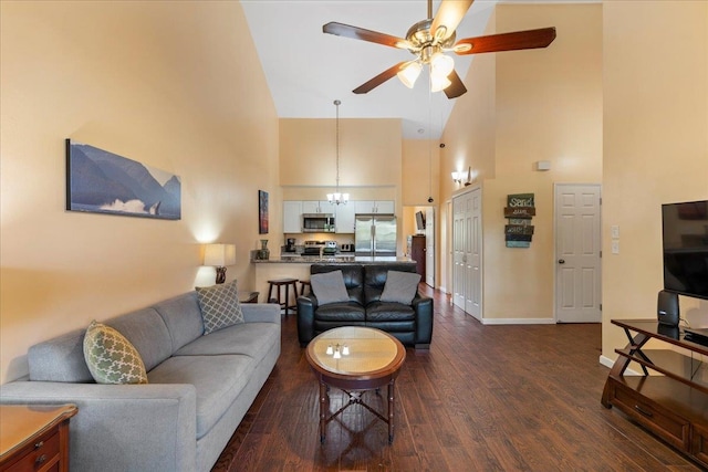 living room featuring high vaulted ceiling, ceiling fan with notable chandelier, and dark wood-type flooring