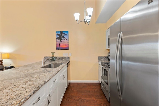 kitchen with pendant lighting, sink, dark wood-type flooring, white cabinetry, and stainless steel appliances