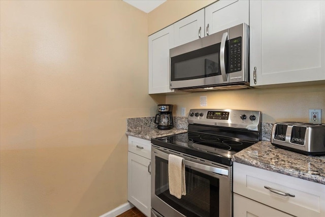 kitchen with white cabinets, light stone counters, and appliances with stainless steel finishes