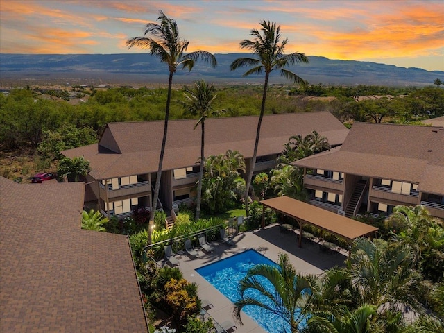 pool at dusk featuring a mountain view and a patio area