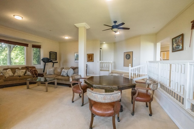 carpeted dining room featuring ceiling fan, crown molding, and decorative columns