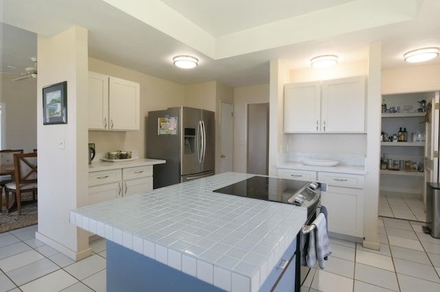 kitchen featuring tile counters, white cabinets, stainless steel appliances, and light tile patterned floors