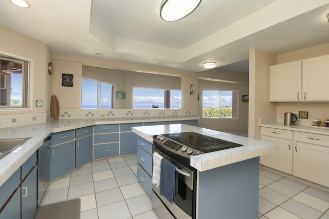 kitchen featuring a center island, blue cabinets, a tray ceiling, white cabinetry, and stainless steel appliances