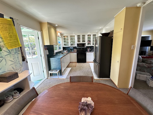 kitchen featuring light carpet, sink, black appliances, and white cabinets