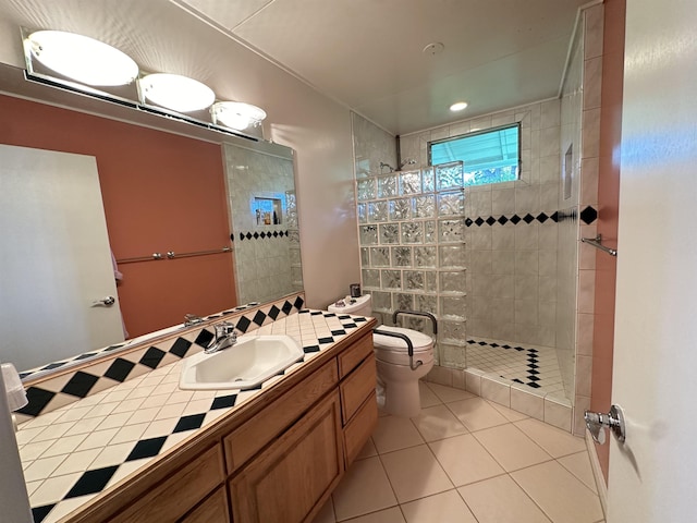 bathroom with vanity, toilet, tile patterned flooring, and a tile shower