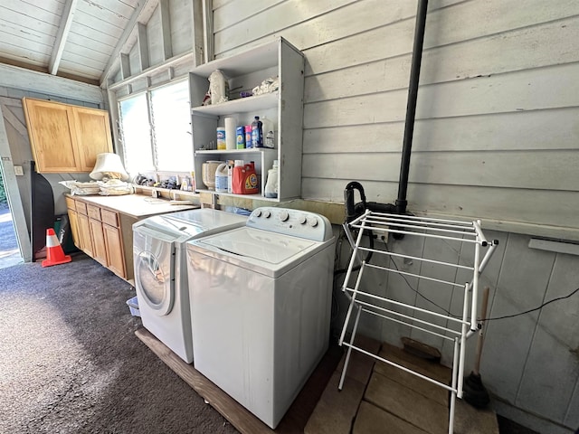 clothes washing area with cabinets, washing machine and clothes dryer, dark carpet, wooden ceiling, and wood walls