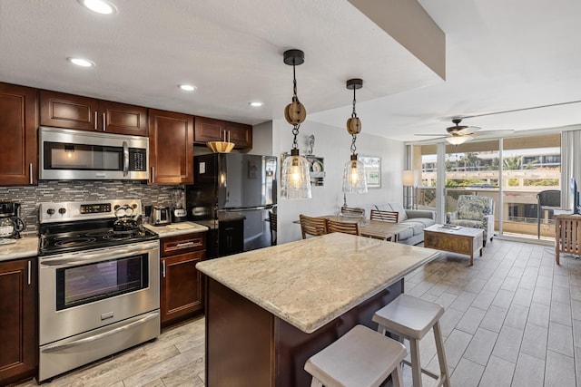 kitchen featuring a center island, hanging light fixtures, a kitchen breakfast bar, backsplash, and stainless steel appliances