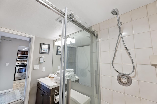 bathroom featuring a textured ceiling, vanity, backsplash, hardwood / wood-style flooring, and a shower with shower door