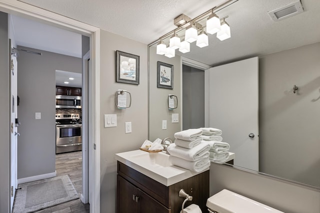 bathroom with a textured ceiling, toilet, vanity, and tasteful backsplash