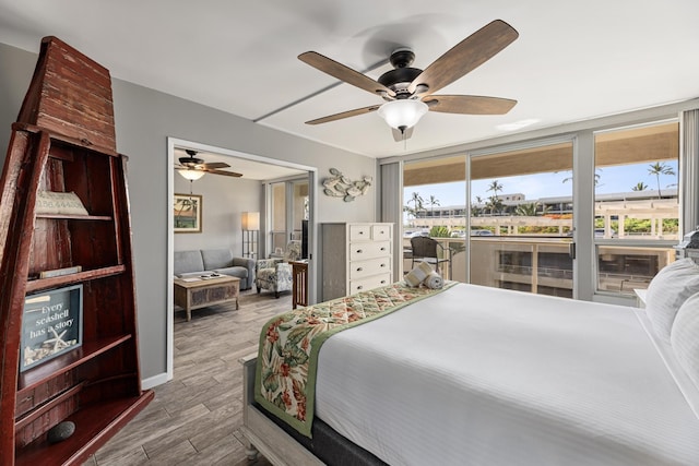 bedroom with ceiling fan, a wall of windows, and access to outside